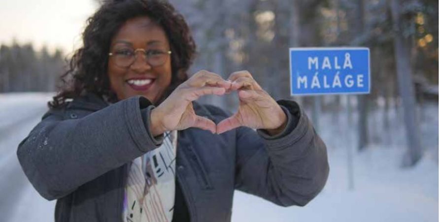 Kvinna formar händerna till ett hjärta framför Malå skylten