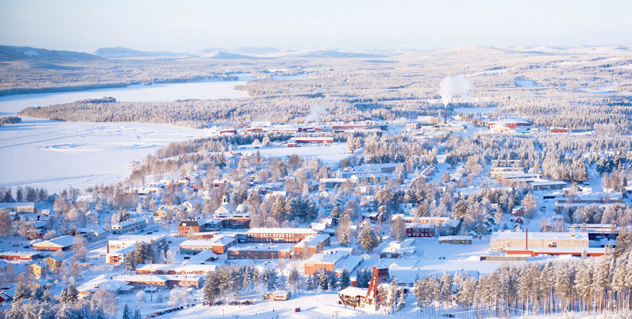 Bild tagen från Tjamstanberget över snötäckt Malå samhälle en solig vinterdag.