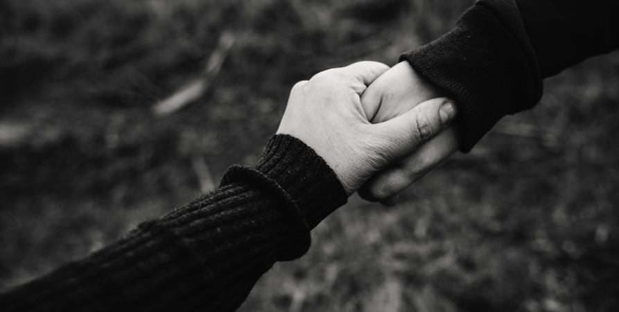 En svartvit bild på två händer som håller varandra. 