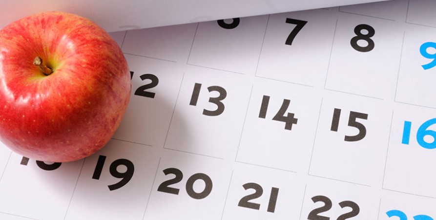 Almancka med datum som ligger ner och ett rött äpple som ligger ovanpå.