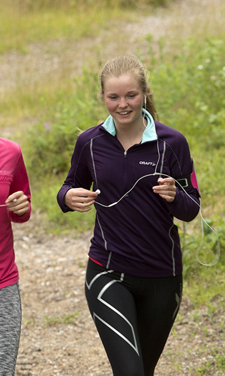 Två kvinnor som joggar bredvid varandra i motionsspåret. Se ser glada ut.