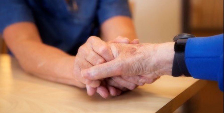 Personal som håller äldre människas hand
